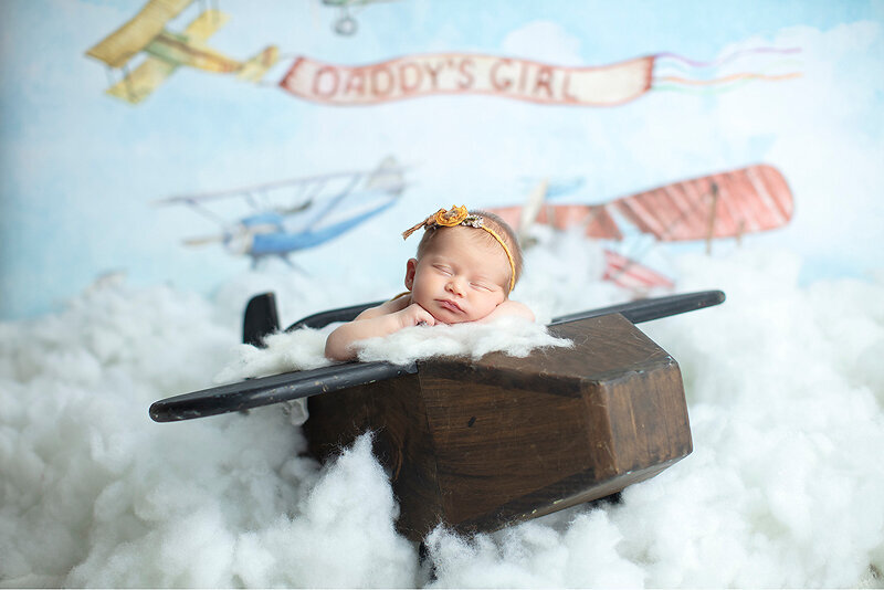 Newborn girl in wooden airplane by Dallas newborn photographer.