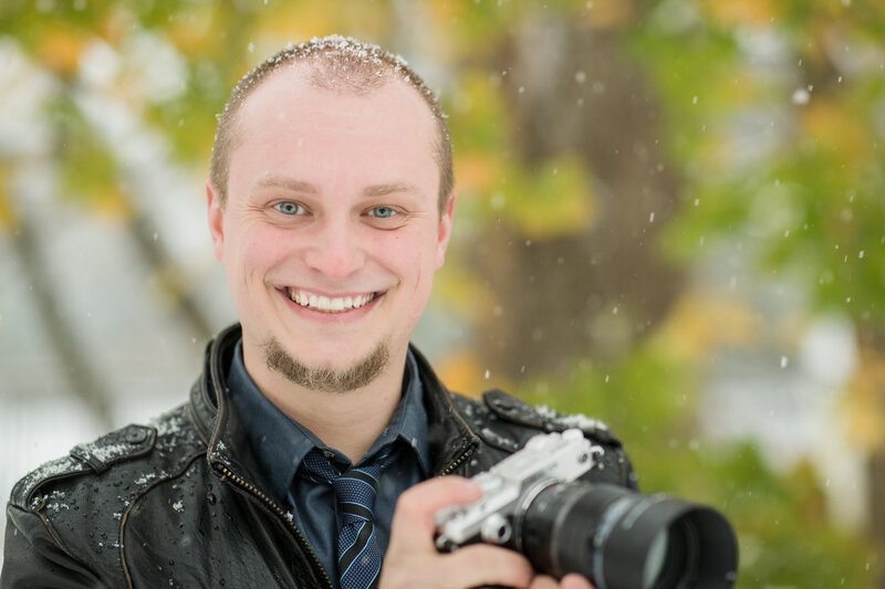 Travis Stitt standing in a snowy landscape, ready to capture breathtaking engagement session moments, showcasing his dedication and creativity as a professional photographer.