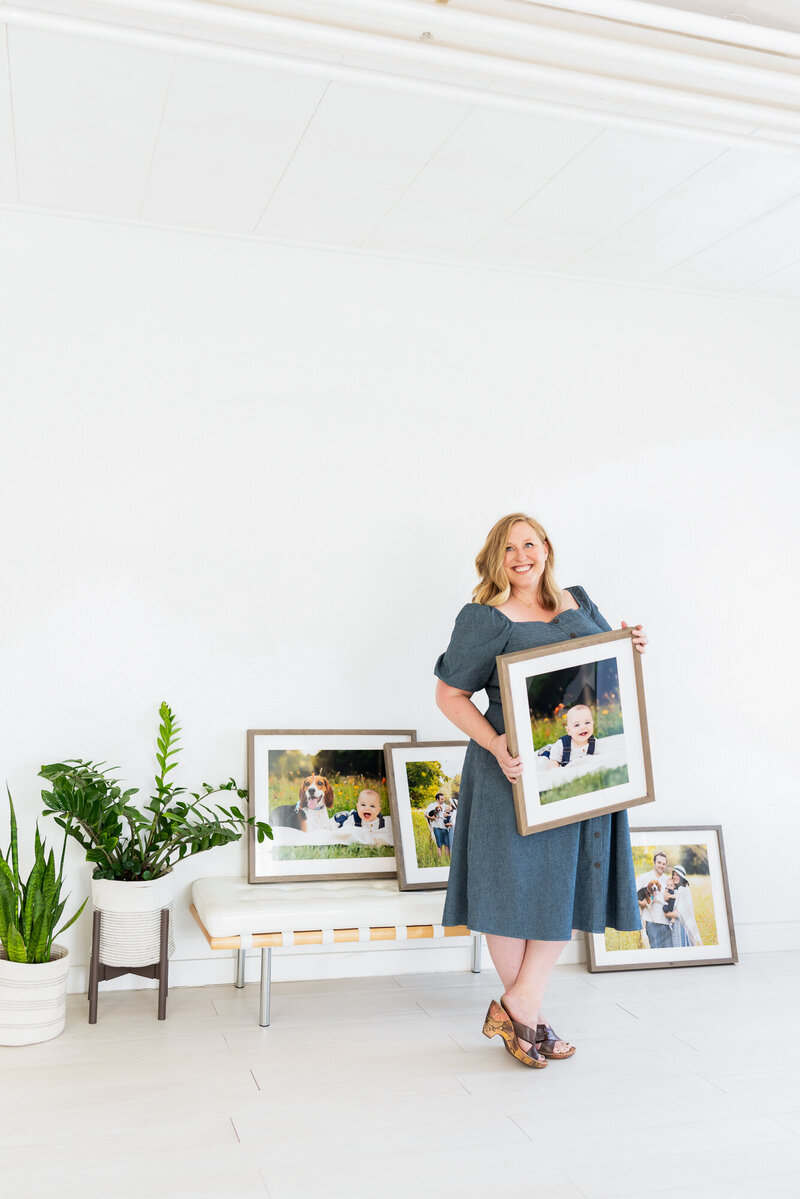 Tiffany Hix holding a framed portrait in her family photography studio in Boise