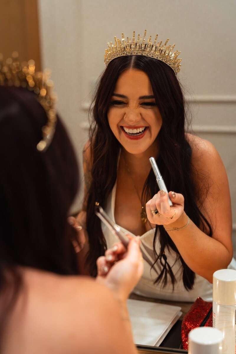 Woman smiling in mirror putting on lipstick