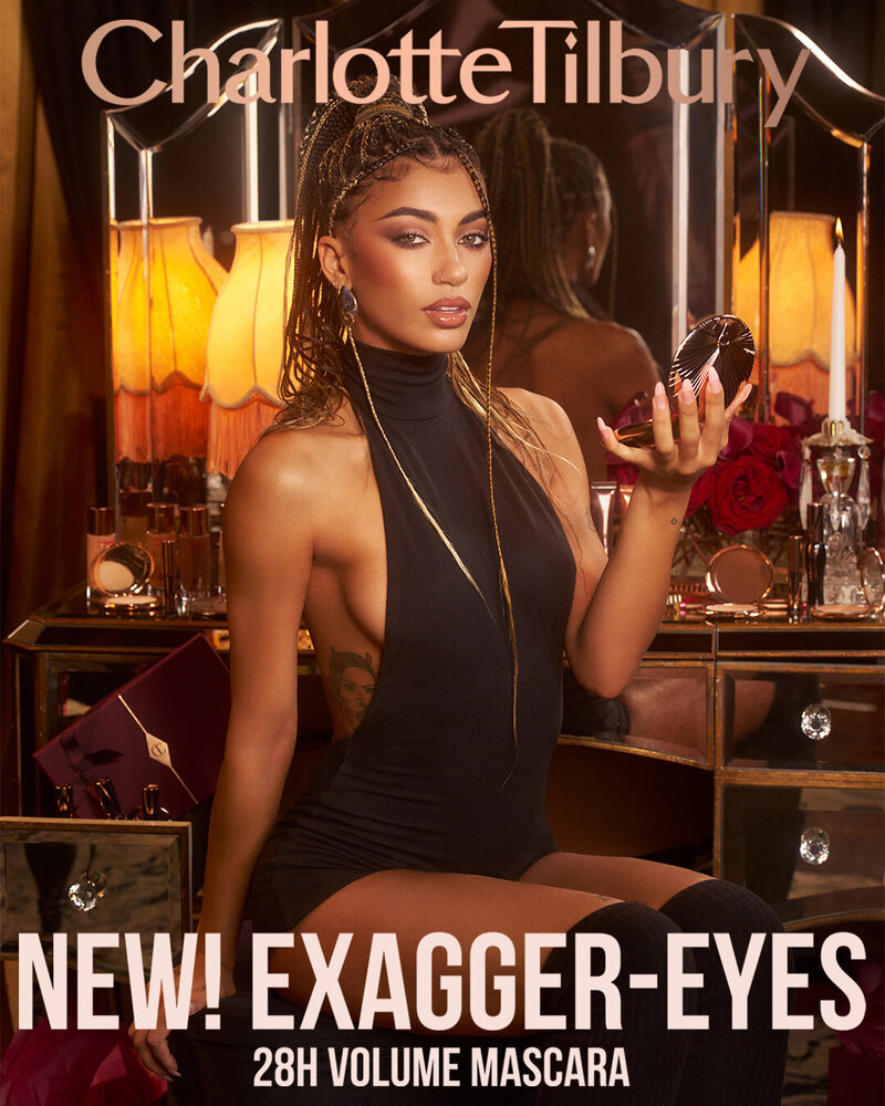 Charlotte Tilbury Exagger-Eyes 28H Volume Mascara campaign featuring Halle Powe, posing confidently with bold makeup in a luxurious setting.