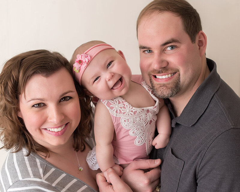 Smiling baby with mom and dad in family portrait by Laura King Photography