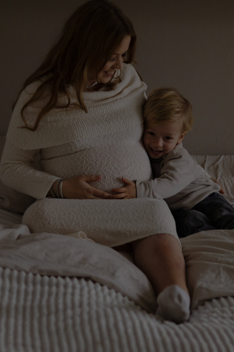 Een vrouw en een kind zitten samen op een bed, genietend van een moment van samenzijn en ontspanning.