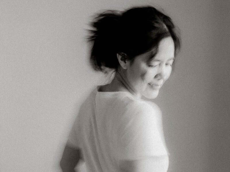 Soft black and white self-portrait of Canyon Lake newborn photographer Jess Young, captured in motion to reflect the gentle, fleeting rhythm of motherhood and the heart behind her in-home sessions.