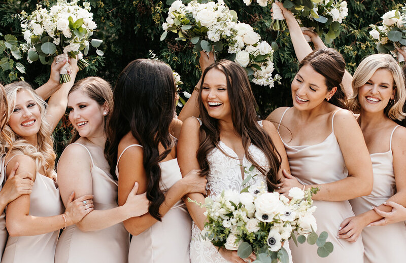 Bride smiling at all her bridesmaids standing around her