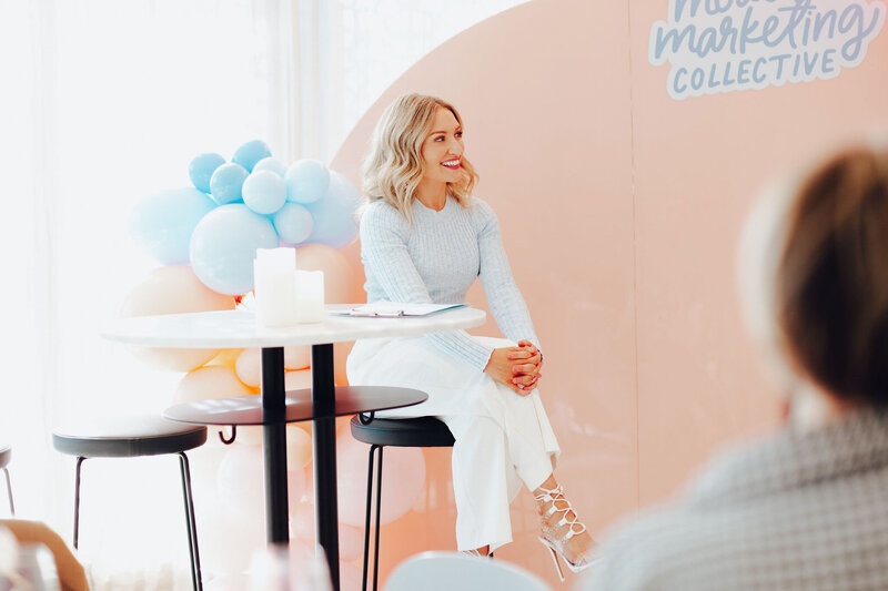 Emily Osmond sitting at a chair as she speaks at a professional marketing event.