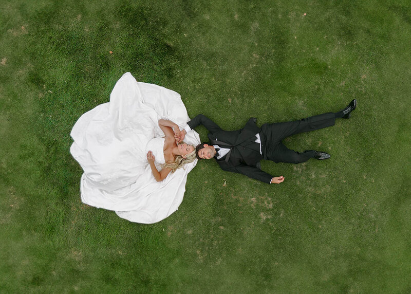 Aerial shot of bride and groom laying on the ground while smiling taken by Natural light wedding photography Portland