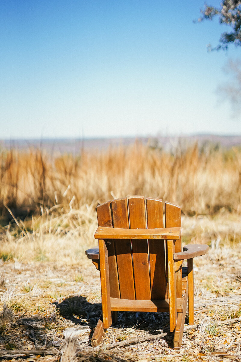 Wooden Adirondack chair outside in a grassy area