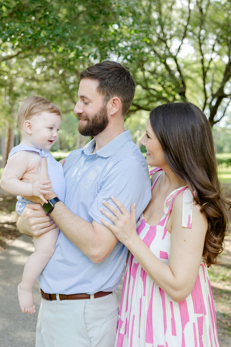 Mother and father holding a baby smiling at him during family mini session