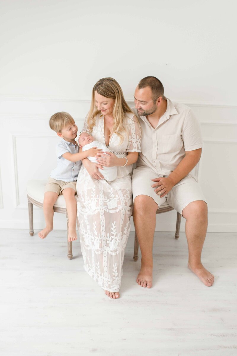 Die Familienfotografie Bielefeld ist indoor im weiß-gehaltenem Foto-Atelier bei Familienfotografin Josephine Böck entstanden. Dabei hält die Mama das Neugeborene umgeben von ihrem Ehemann und kleinen Sohn.