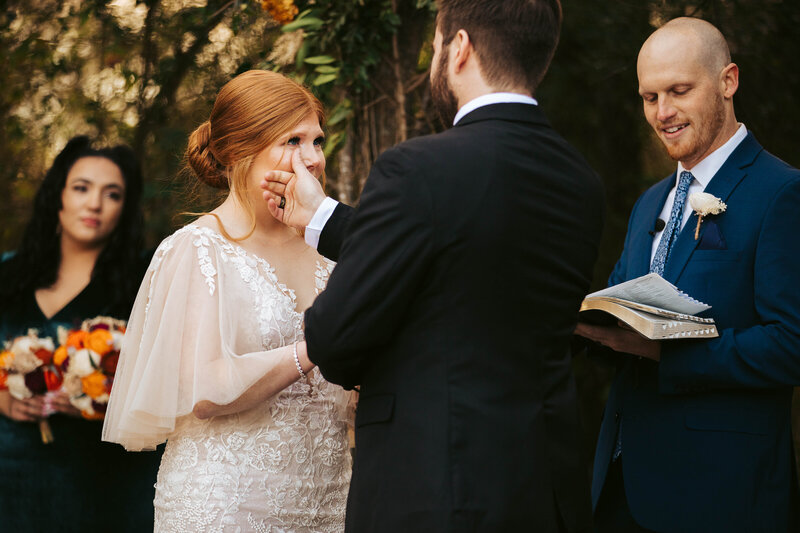 groom wiping away bride's tears during wedding ceremony