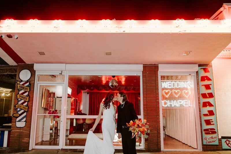 A couple kisses one another in Las Vegas in front of a chapel.