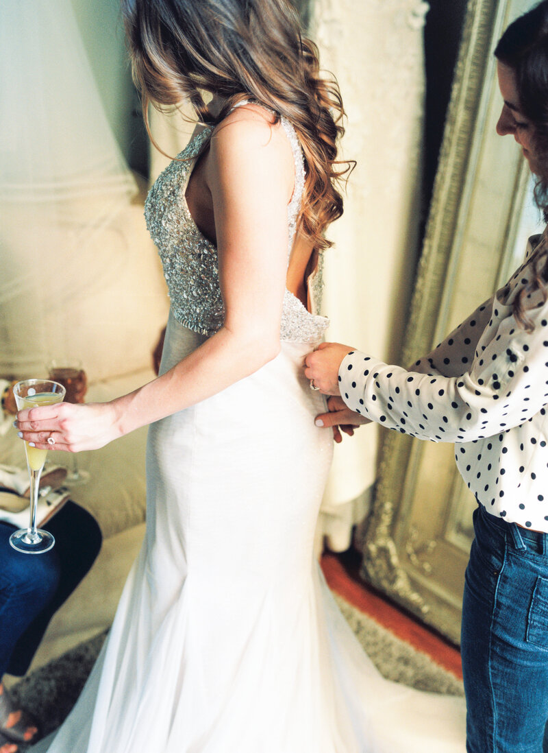 Sister zipping up brides gown at gown appointment