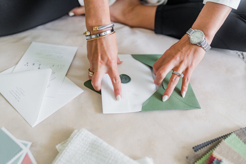 close up of hands crafting a green wedding invitation