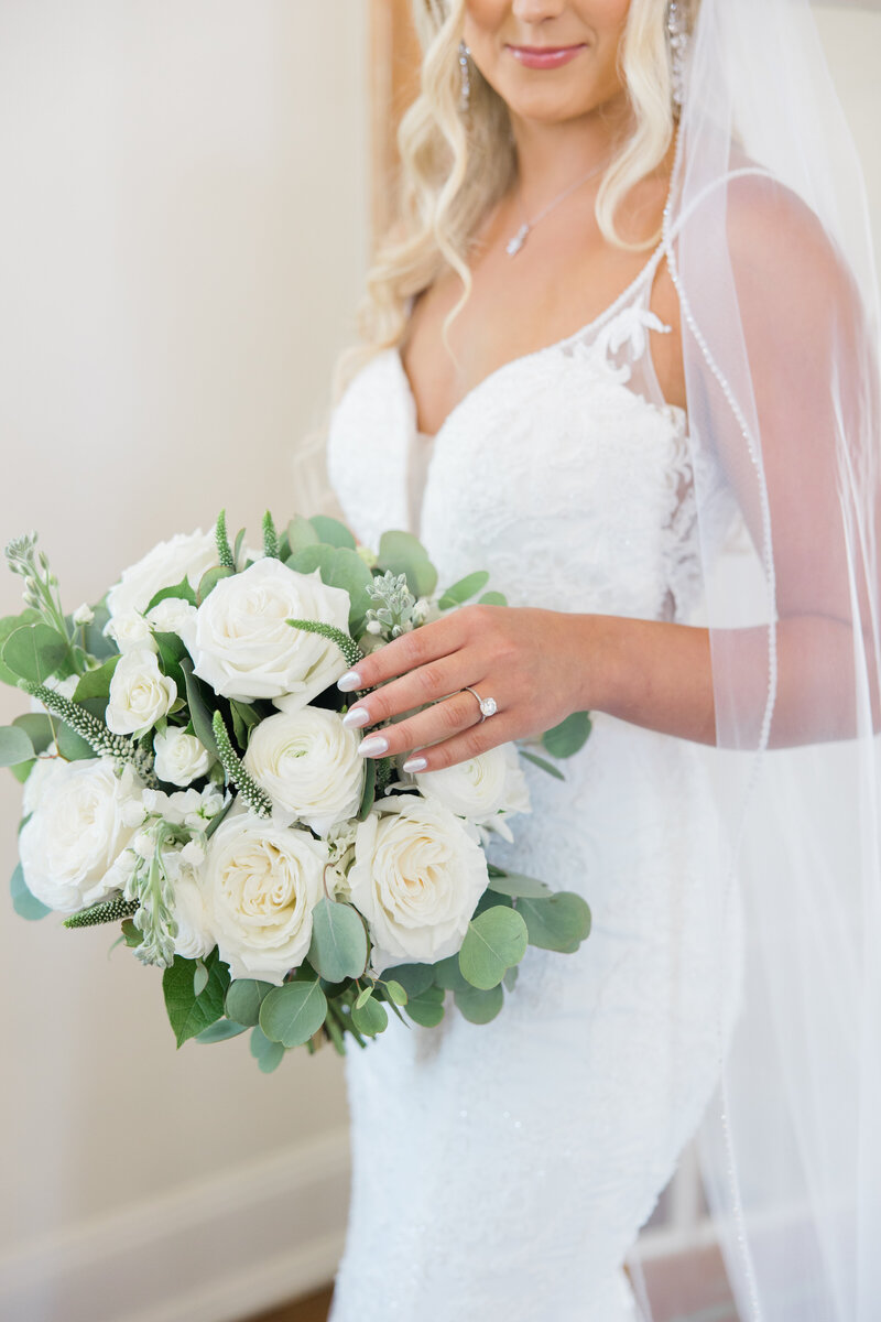 bride in a white wedding dress holding a bouquet of white roses