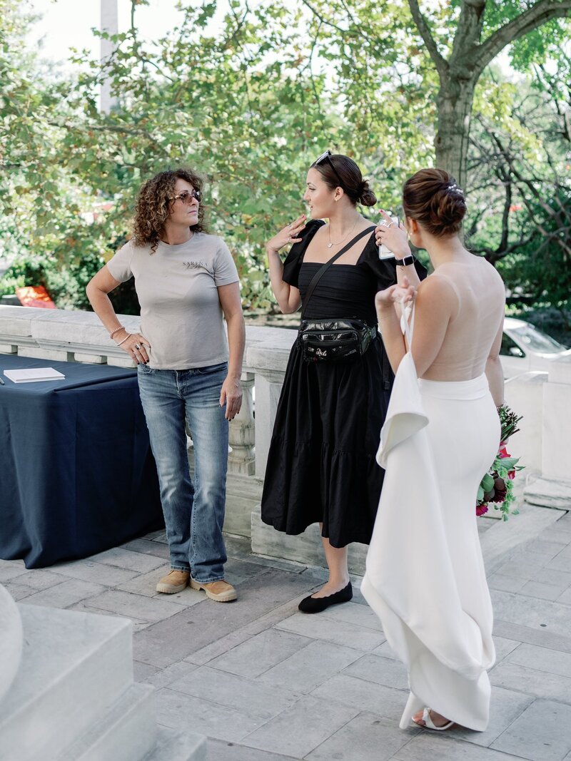 Wedding planner in black dress gives instructions to florist and bride at DAR Constitution Hall