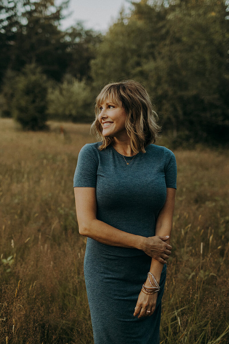 heather boren in a field at golden hour middle aged photographer with denim blue dress on