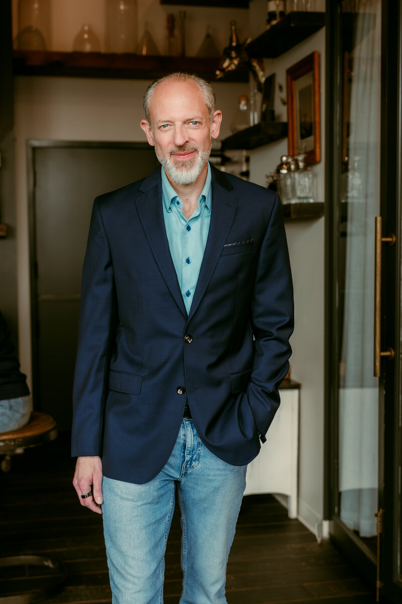 Natural light dating profile photo of a man in a blue blazer and jeans, standing confidently in a modern, casual setting — Minneapolis dating photographer.
