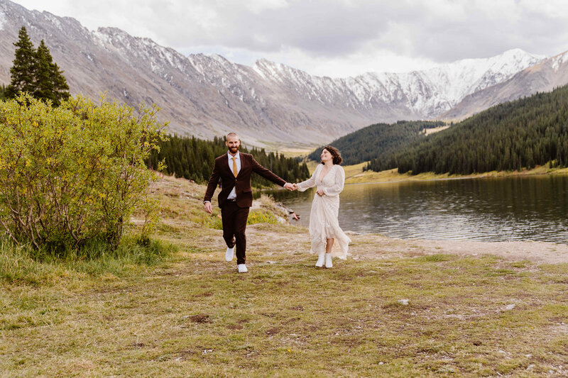Couple runs together hand in hand during their elopement in Leadville, Colorado