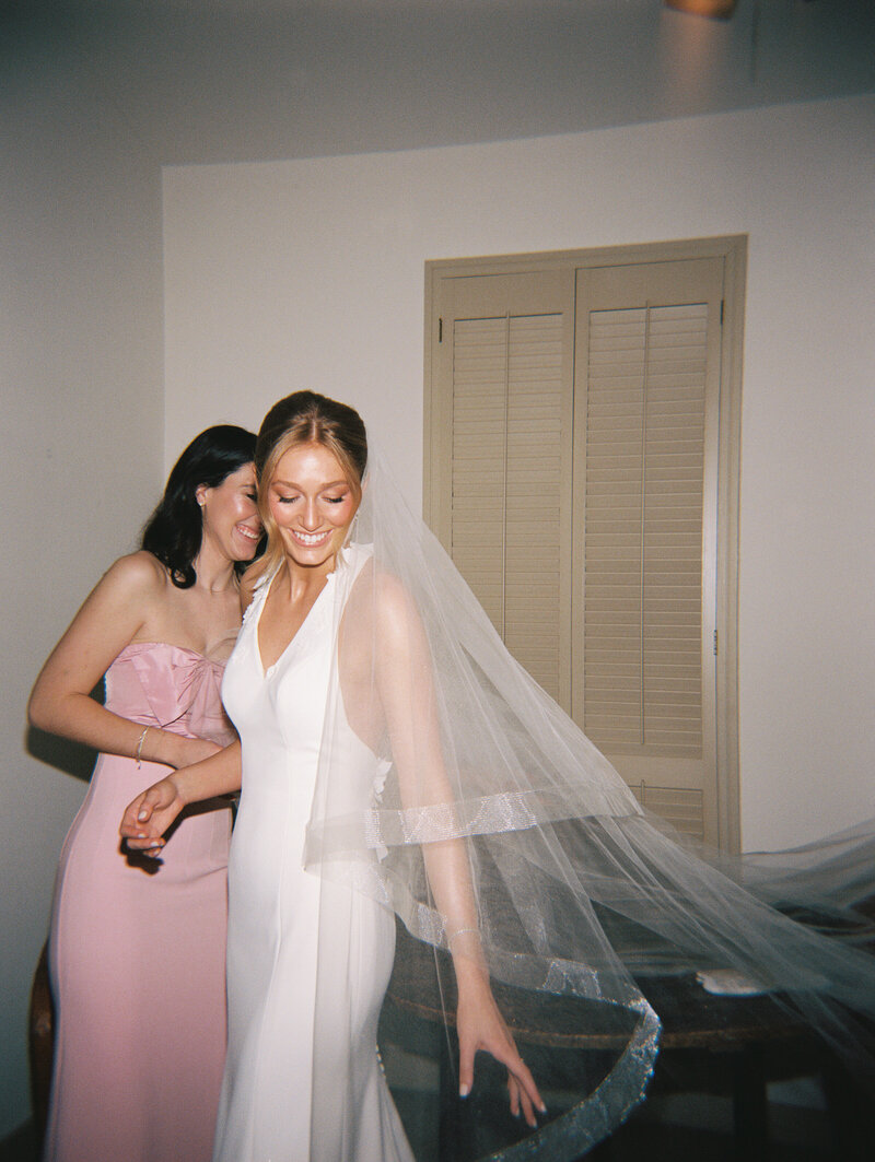 Flash photo of bride adjusting her veil with bridesmaid behind her