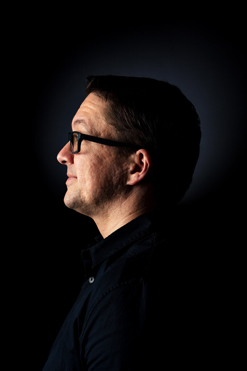 man wearing glasses and black shirt looking into light