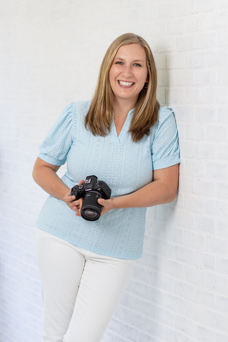 Headshot of Kathleen Jablonski, NH Newborn Photographer,  leaning against the wall in her studio in Manchester NH