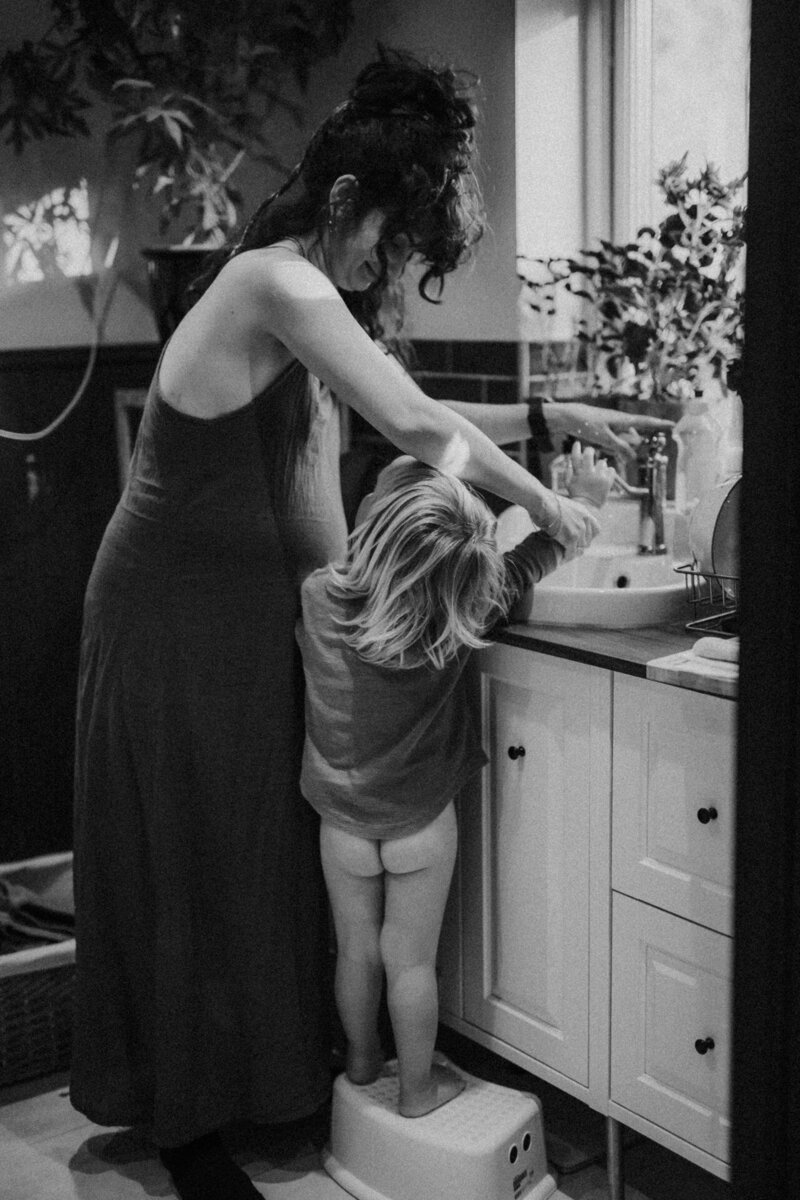 En gravid mamma tvättar sin sons händer. Gravidfotografering Göteborg.