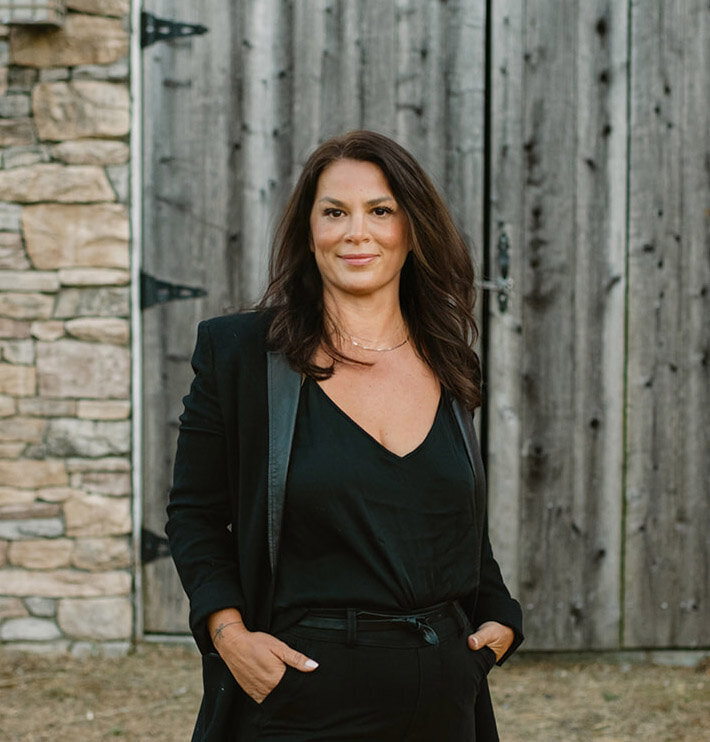 Portrait of Claudia Fulga, a leadership coach based in California, specializing in guiding leaders, entrepreneurs, and creatives through transitions with grounded confidence and a powerful presence. Photographed outdoors in a professional black outfit, embodying confidence and strength.