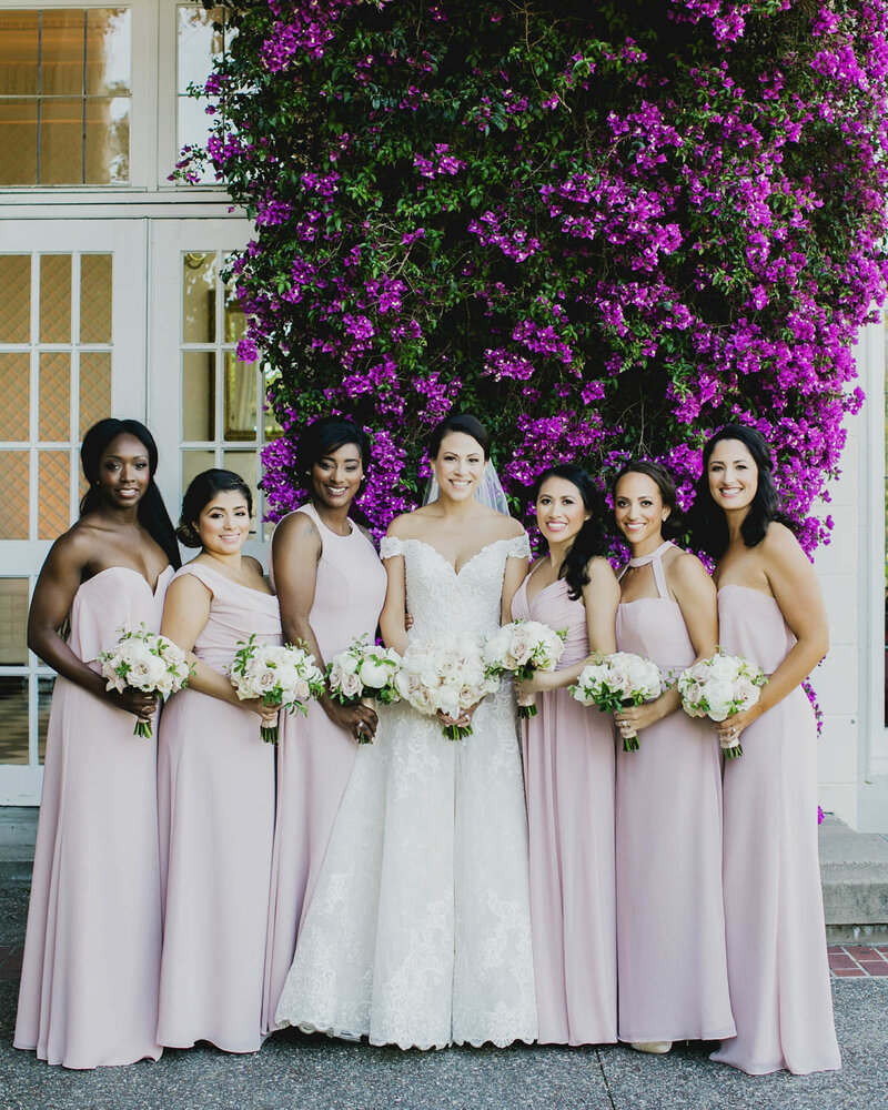 Bridesmaid surround Bride holding bouquets smiling at the camera