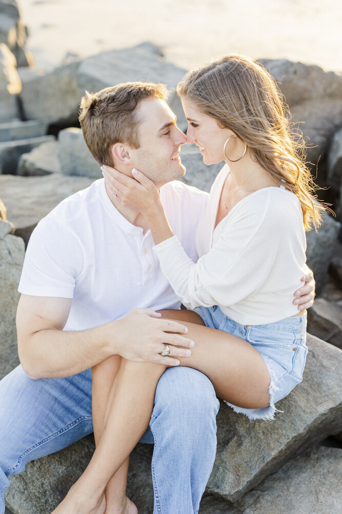 engaged couple about to kiss while sitting on rocks