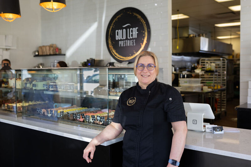 Portrait of the pastry chef Carly Harding standing in front of the pastry display case inside Gold Leaf Pastries in Kamloops BC.