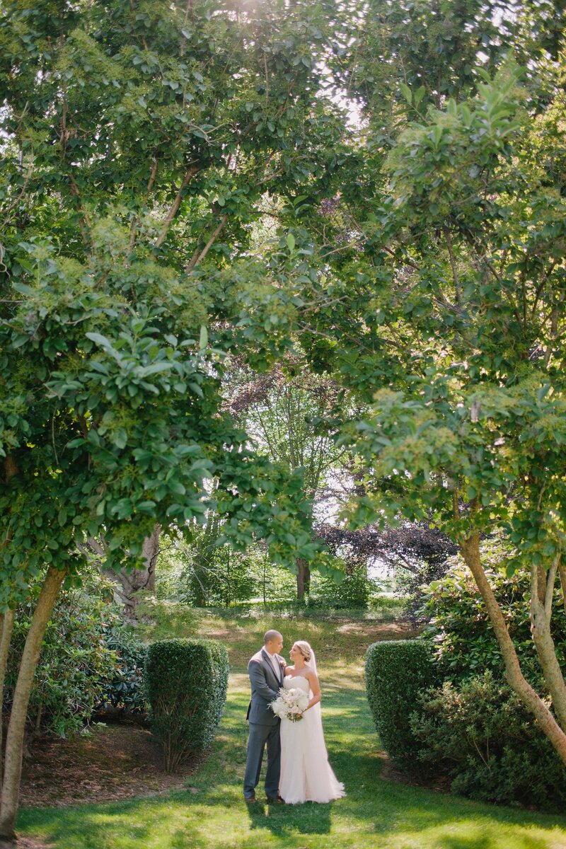 Bride and groom stand in a garden after their wedding ceremony