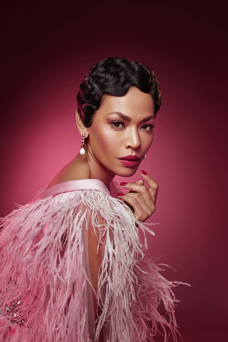Elegant portrait of Amira in a pink, feathered outfit with soft lighting, captured by Ylva Erevall.