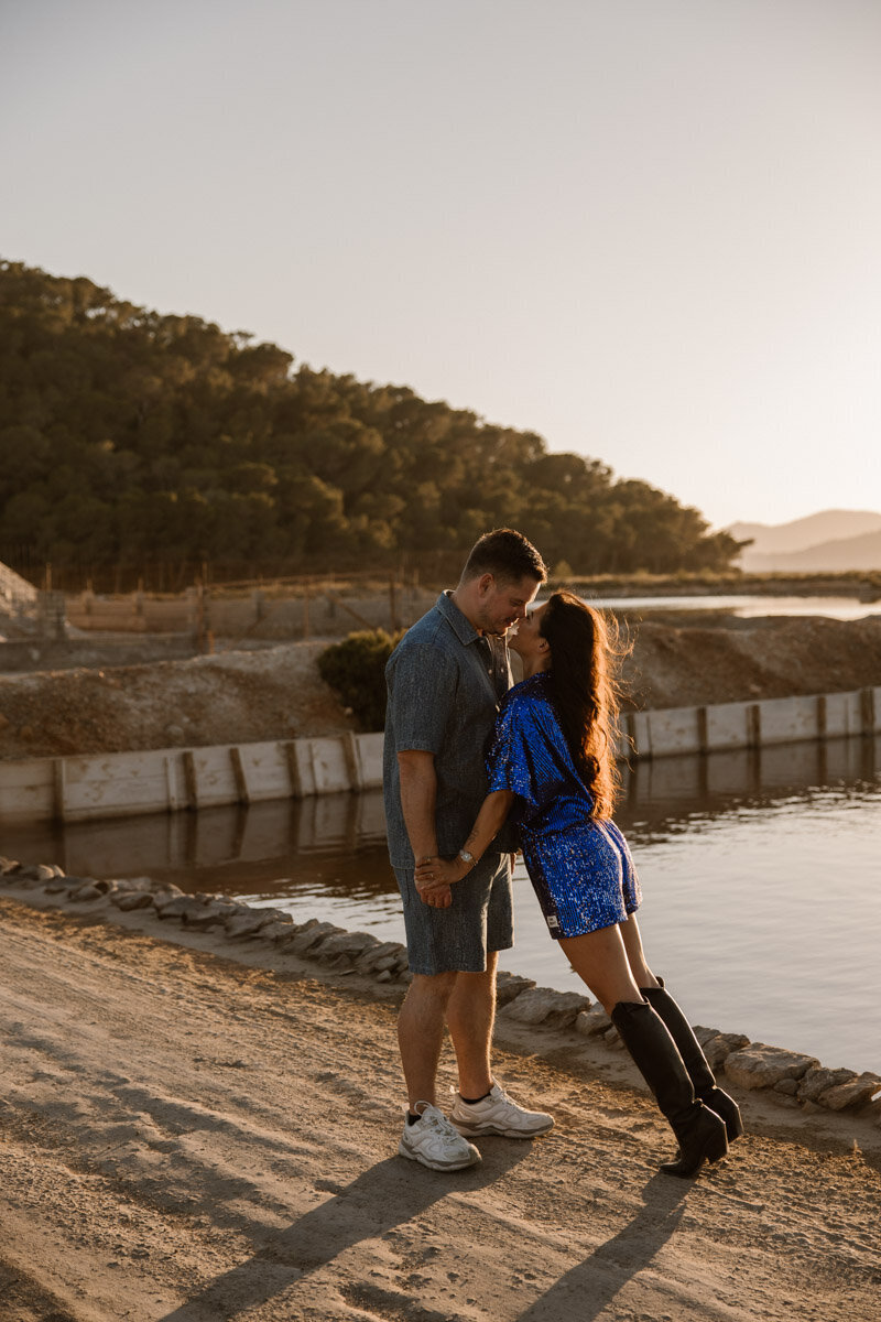 A woman in white clothes is walking on the beach during sunset for a maternity photoshoot on Ibiza.