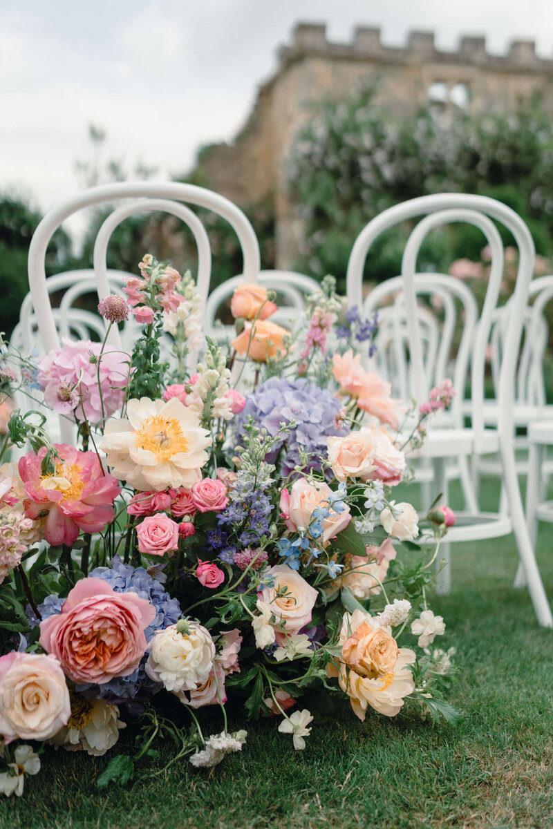 closeup of pink yellow and purple wedding flowers at the back of a wedding ceremony aisle for a garden wedding at euridge manor