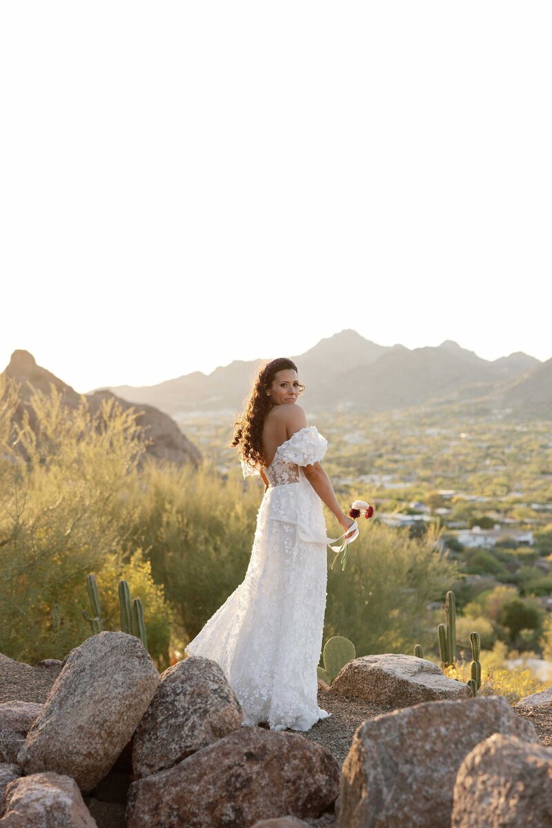Bride looks over her shoulder during sunset in the Paradise Valley mountains.