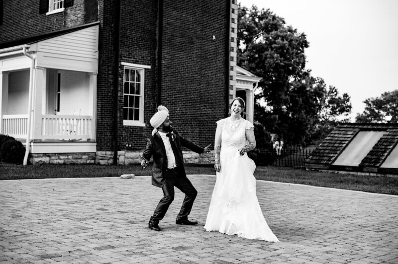 Black and white photo of groom dancing and making his wife laugh after their elopement