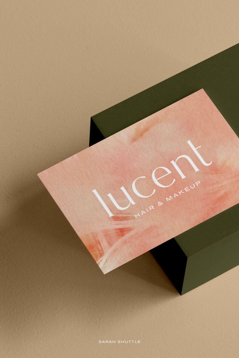 Business card mockup featuring the Lucent Hair & Makeup logotype in a warm, modern beauty brand design.