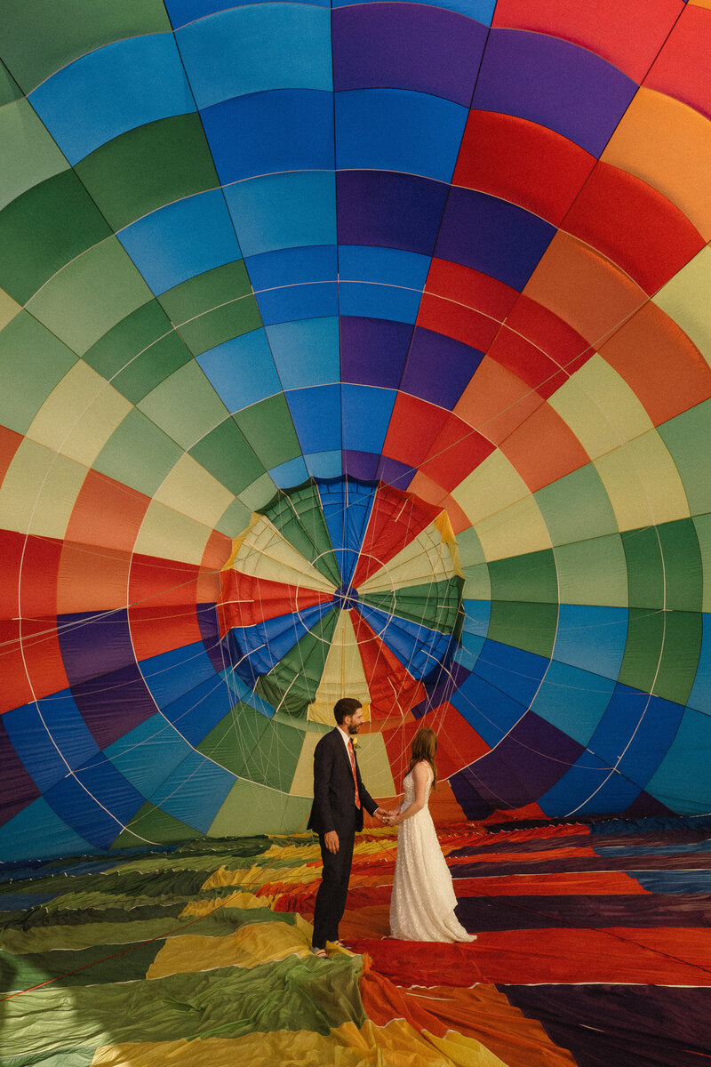 bride and groom standing inside of a hot air balloon