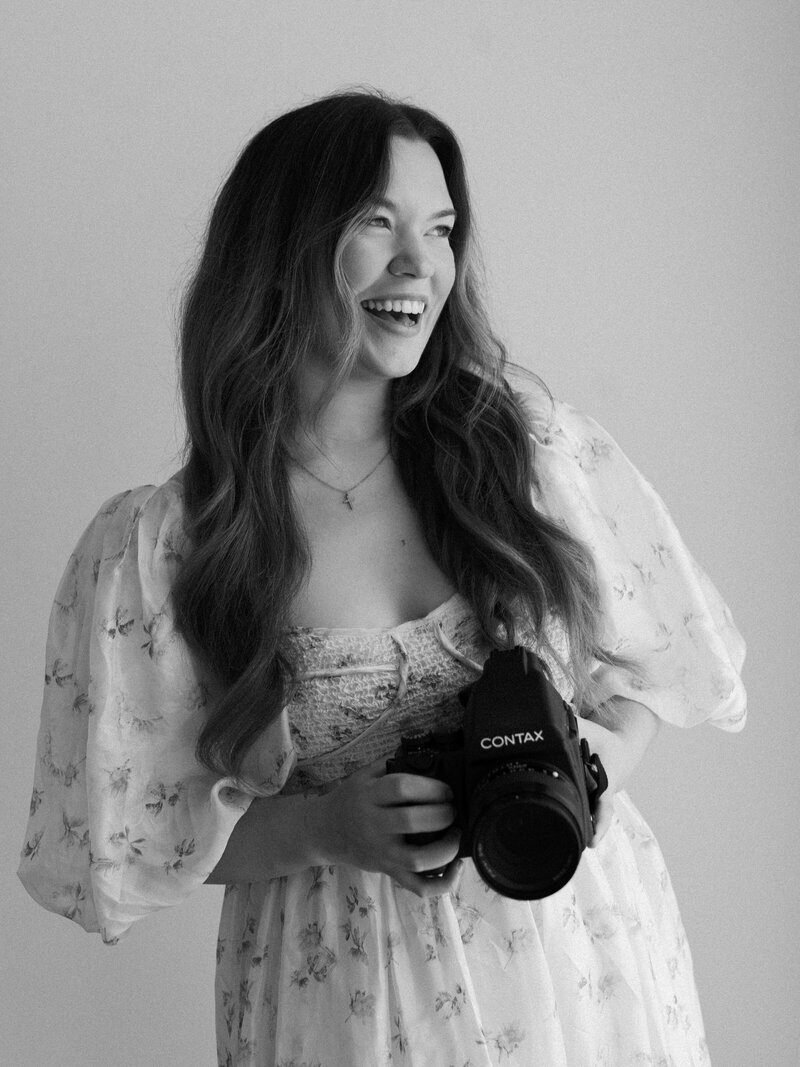Fun film photographer smiling and laughing at camera with floral bouquet