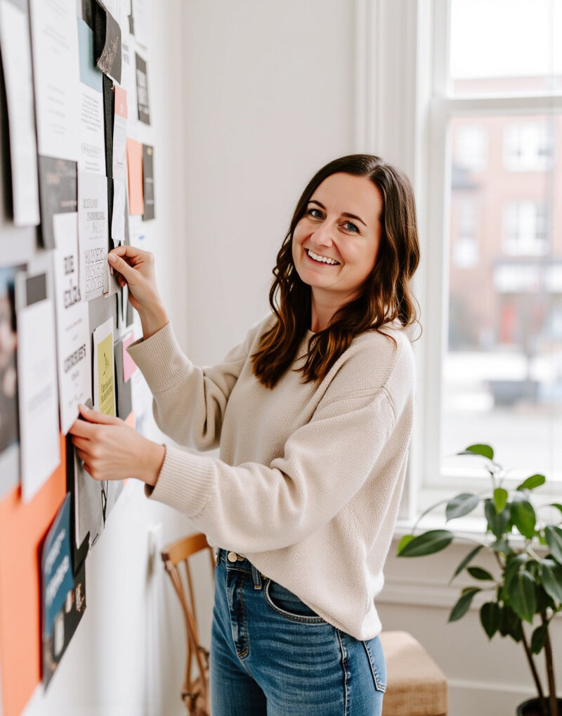 Jordin, the owner of Unica Formo, gazes thoughtfully at pictures on the wall, inspired by her artistic branding work.
