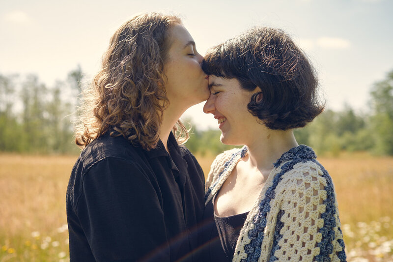 A lesbian couple shares a moment in a sunny flower field in Bellingham.