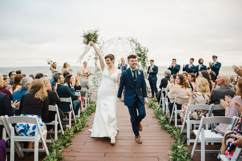 A newlywed couple holding hands and walking back up the aisle after getting married