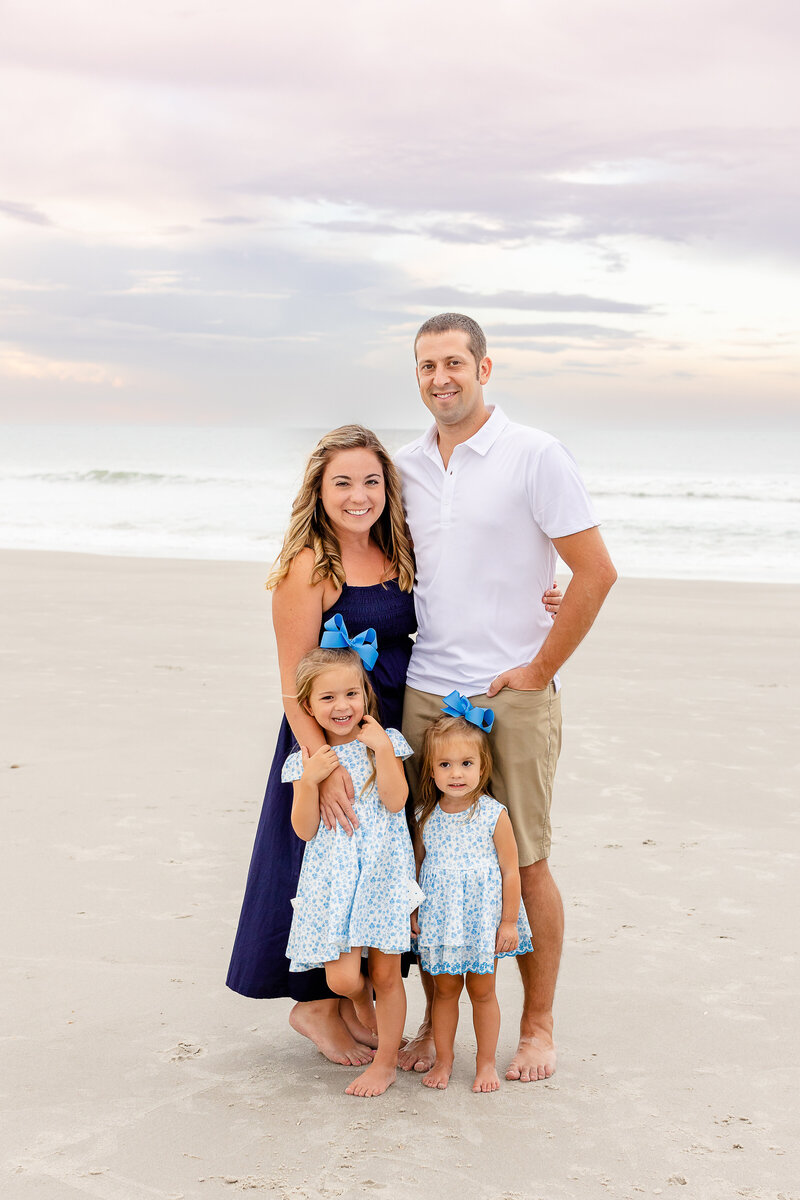 family of four posing on the beach