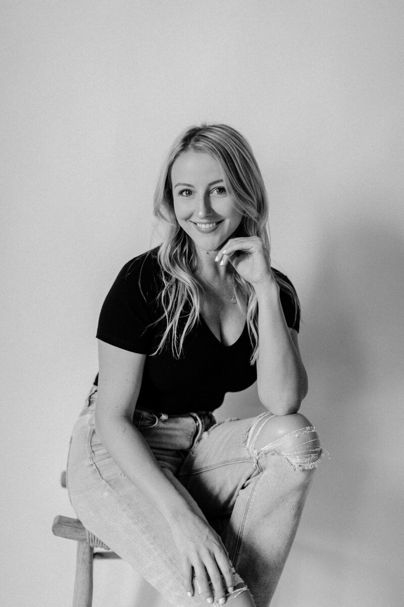 black and white image woman sitting on stool