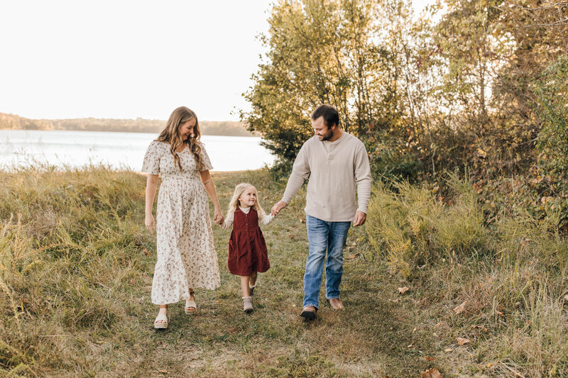 photo of parents with daughter near a lake at sunset