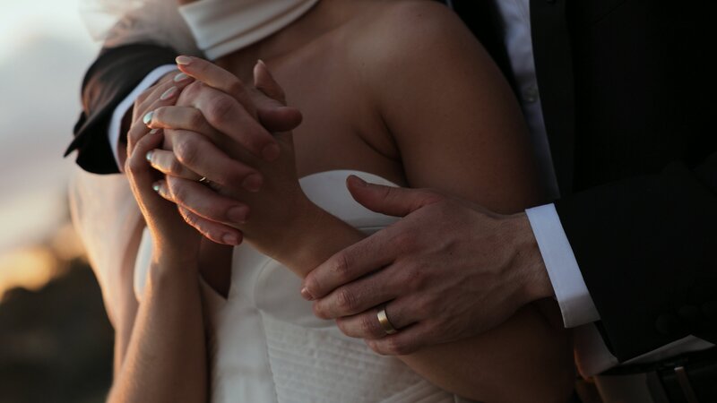 elegant bride and groom hold hands and gaze at each other lovingly, black and white
