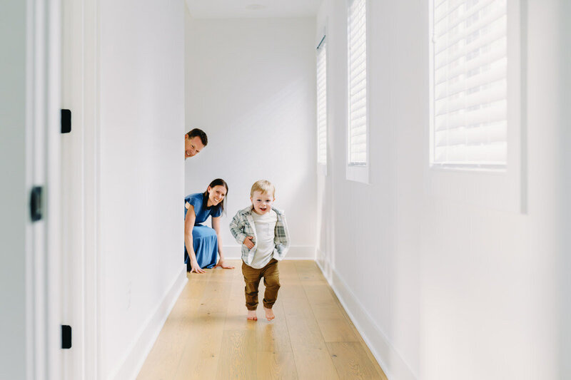 little boy running down hallway with parents looking