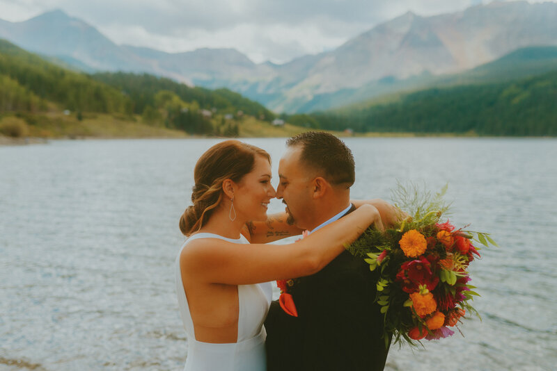 Bride and groom cuddling in front of lake and mountains during their Telluride elopement captured by Colorado elopement photographer by Mikayla Renee Photo
