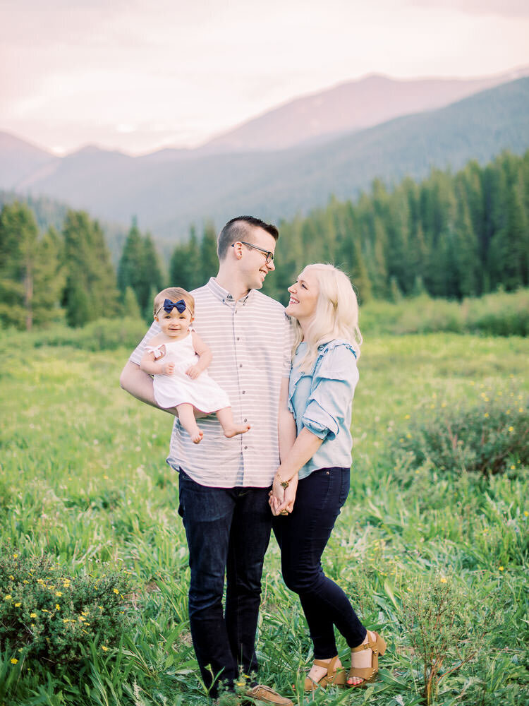 Mom and dad smile with daughter during their mountain view photoshoot in Breckenridge, Colorado